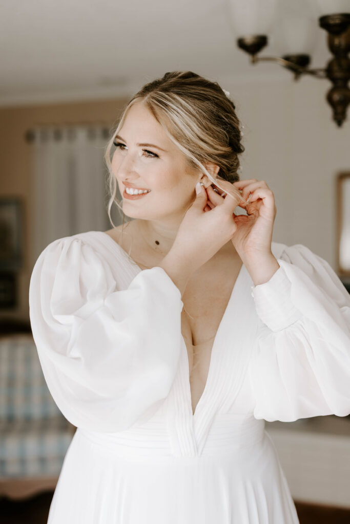 The bride puts in her earrings in getting ready photos